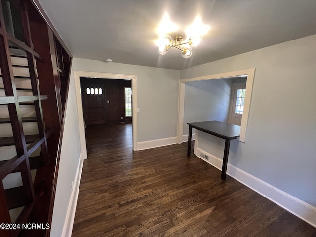 foyer with dark wood finished floors, a wealth of natural light, a notable chandelier, and baseboards