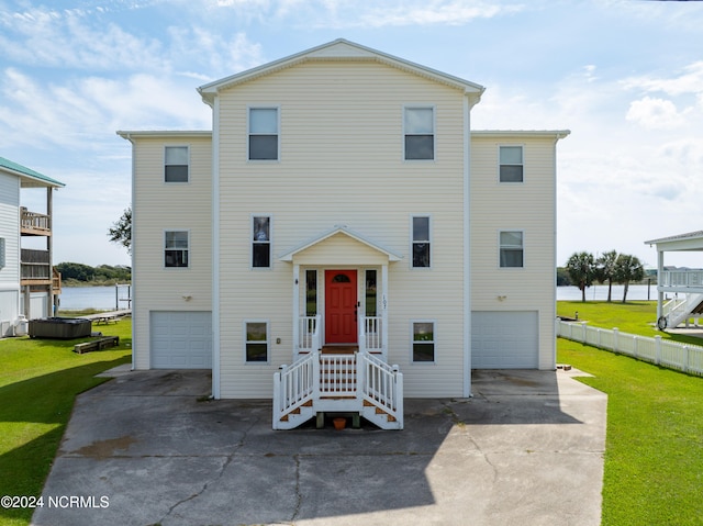 view of front of home with a garage, a water view, and a front lawn