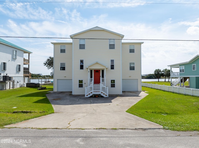 view of front of home featuring a front yard, a water view, and a garage