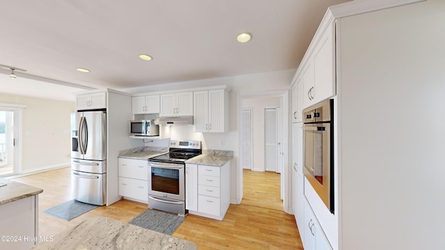 kitchen with white cabinets, stainless steel appliances, light stone countertops, and light hardwood / wood-style floors