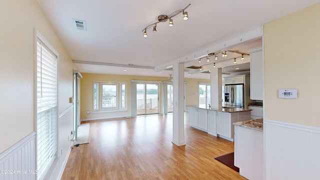 kitchen featuring stainless steel fridge with ice dispenser, rail lighting, light hardwood / wood-style flooring, and white cabinetry