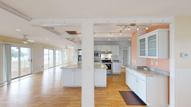 kitchen featuring white cabinets, ceiling fan, light wood-type flooring, appliances with stainless steel finishes, and light stone counters