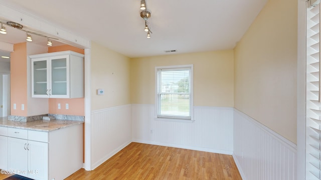 unfurnished dining area featuring light wood-type flooring and track lighting