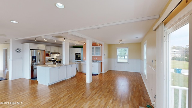 kitchen featuring light wood-type flooring, rail lighting, stainless steel appliances, a kitchen island, and white cabinetry