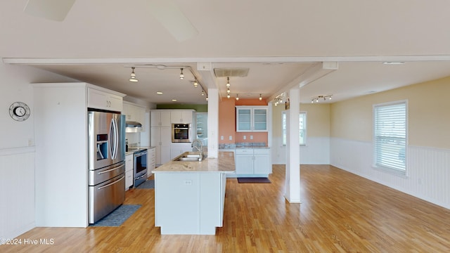 kitchen with stainless steel appliances, white cabinetry, a kitchen island with sink, and light hardwood / wood-style flooring