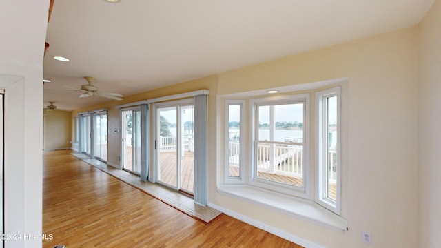 spare room with a wealth of natural light, light hardwood / wood-style flooring, a water view, and ceiling fan