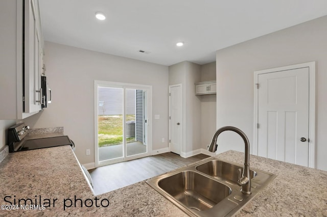 kitchen with black stove, dark hardwood / wood-style floors, white cabinets, and sink