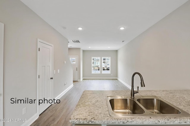 kitchen with light hardwood / wood-style flooring, sink, and light stone counters