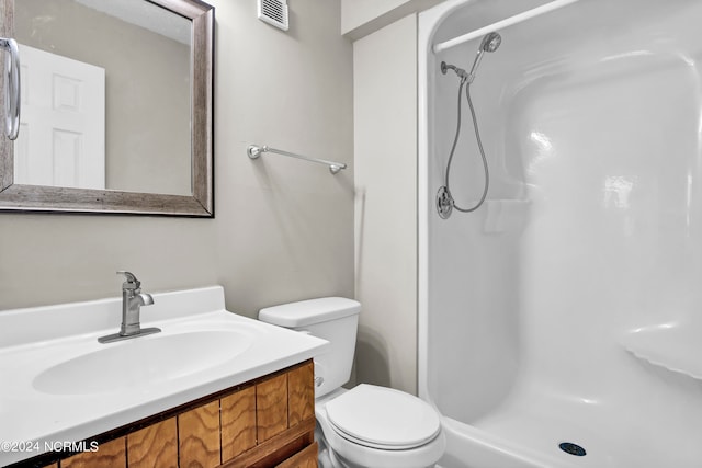 bathroom with vanity, a shower, and toilet