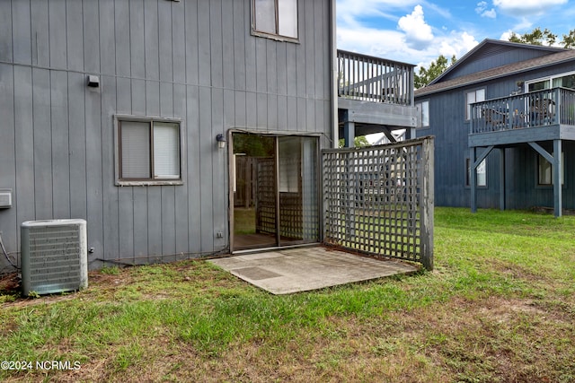 back of property with central AC unit, a deck, and a lawn