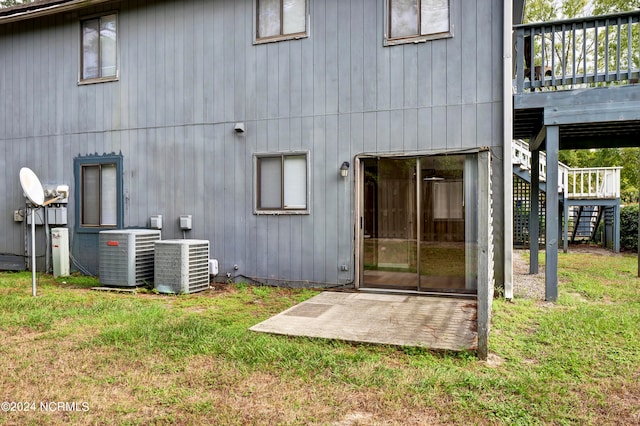 rear view of house featuring cooling unit, a deck, and a yard