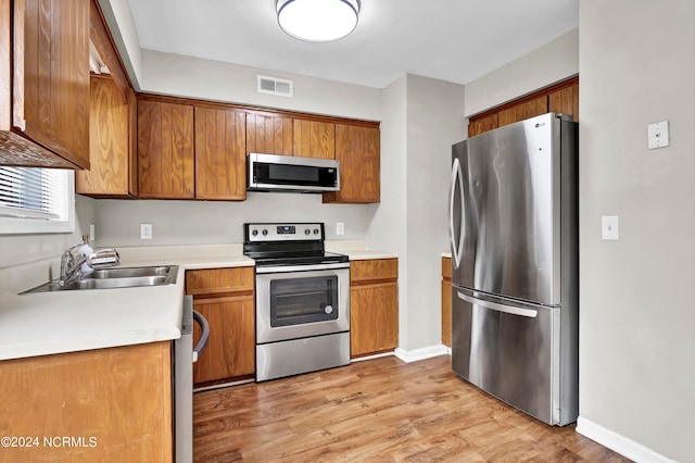 kitchen featuring appliances with stainless steel finishes, light hardwood / wood-style floors, and sink