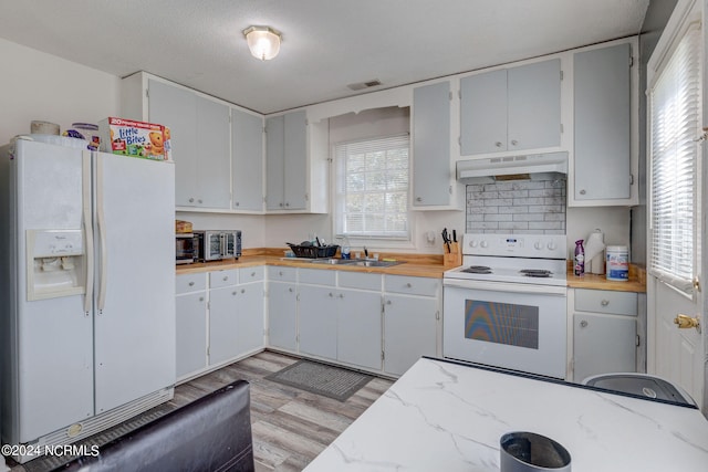 kitchen featuring backsplash, white appliances, plenty of natural light, and sink