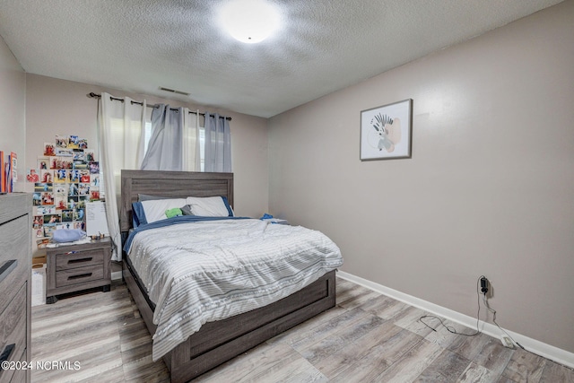 bedroom featuring light hardwood / wood-style flooring and a textured ceiling