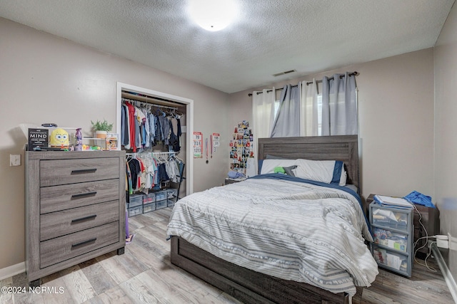 bedroom featuring a textured ceiling, light hardwood / wood-style flooring, and a closet