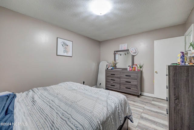 bedroom with light hardwood / wood-style flooring and a textured ceiling