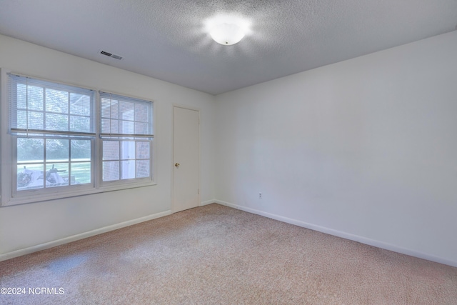 carpeted spare room featuring a textured ceiling