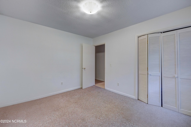 unfurnished bedroom with a closet, light colored carpet, and a textured ceiling