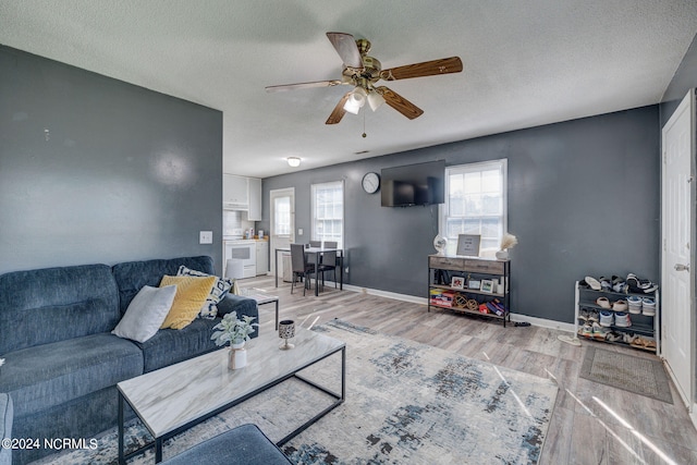 living room with ceiling fan, a textured ceiling, and hardwood / wood-style floors