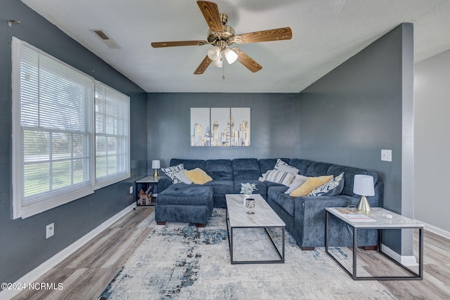 living room with ceiling fan, hardwood / wood-style flooring, and a textured ceiling