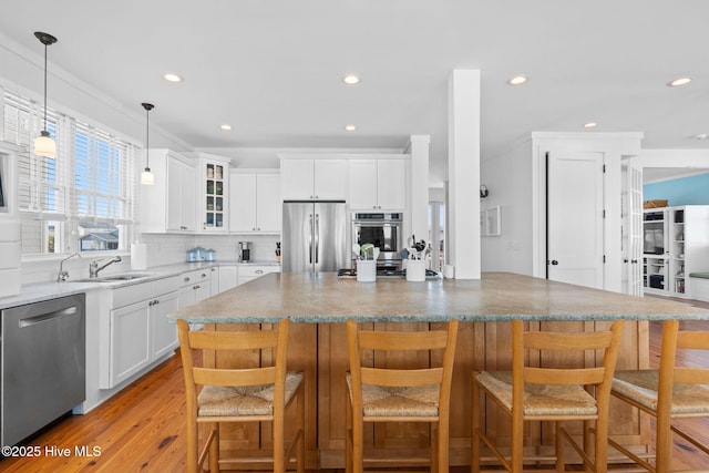 6615 W Beach Dr, Oak Island, NC 28465 - kitchen featuring stainless steel appliances, glass insert cabinets, light wood-style floors, tasteful backsplash, and white cabinets