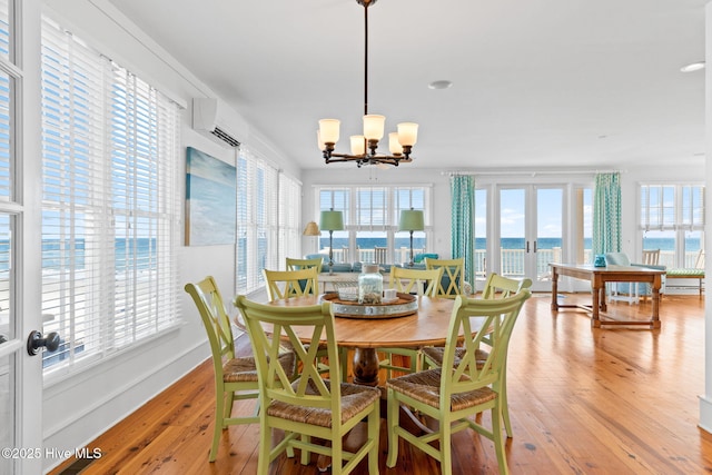 6615 W Beach Dr, Oak Island, NC 28465 - dining room with a wall mounted AC, light wood-style flooring, a chandelier, and baseboards