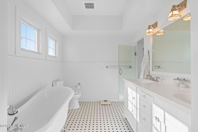 6615 W Beach Dr, Oak Island, NC 28465 - bathroom with a soaking tub, double vanity, a wainscoted wall, and an enclosed shower