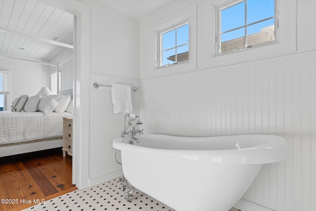 6615 W Beach Dr, Oak Island, NC 28465 - bathroom featuring healthy amount of natural light, a soaking tub, ensuite bath, wainscoting, and a decorative wall