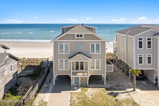 6615 W Beach Dr, Oak Island, NC 28465 - view of front facade featuring a carport, concrete driveway, and view of water and beach
