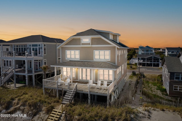 6615 W Beach Dr, Oak Island, NC 28465 - back of property with a shingled roof, a deck, and stairway