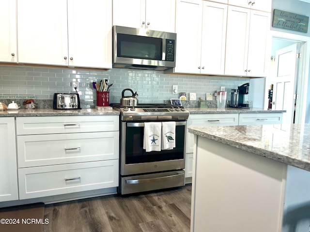 kitchen with appliances with stainless steel finishes, backsplash, dark hardwood / wood-style flooring, and white cabinets