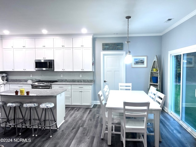 kitchen featuring appliances with stainless steel finishes, white cabinetry, tasteful backsplash, pendant lighting, and dark hardwood / wood-style floors