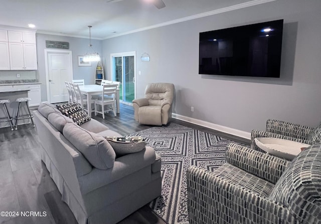 living room with ornamental molding, ceiling fan, and dark wood-type flooring