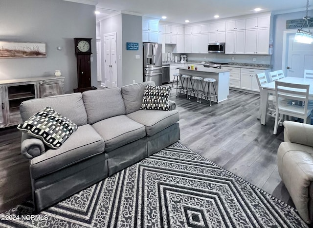 living room with ornamental molding, sink, and hardwood / wood-style flooring