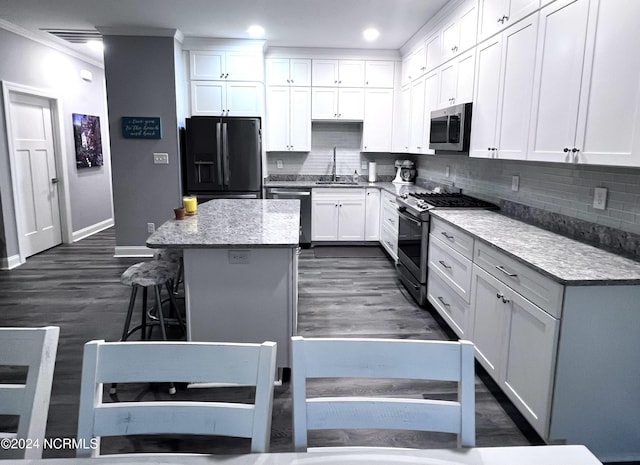 113 Evergreen Ln, Pine Knoll Shores, NC 28512 - kitchen featuring appliances with stainless steel finishes, a kitchen island, baseboards, backsplash, and white cabinetry