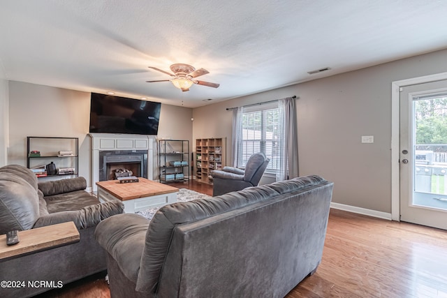 living room with a textured ceiling, wood-type flooring, ceiling fan, and plenty of natural light