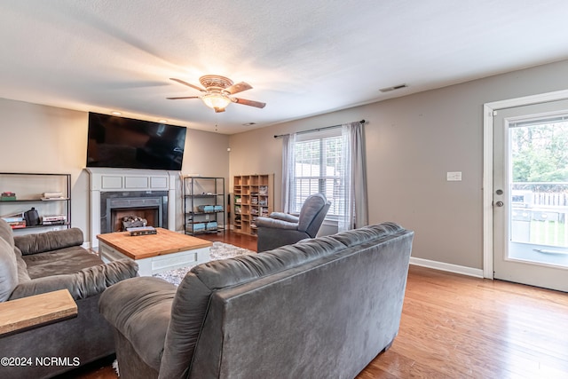 living room featuring light hardwood / wood-style floors, ceiling fan, and a textured ceiling