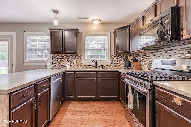 kitchen featuring appliances with stainless steel finishes, light hardwood / wood-style floors, backsplash, kitchen peninsula, and sink