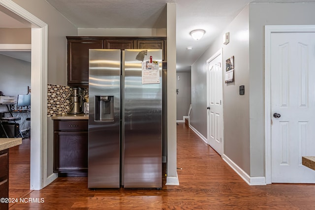 kitchen with backsplash, dark brown cabinets, dark hardwood / wood-style floors, and stainless steel fridge with ice dispenser