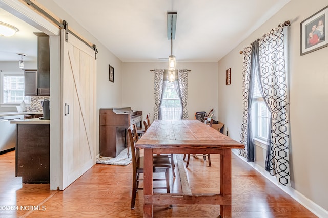 dining room featuring light hardwood / wood-style flooring, a healthy amount of sunlight, and a barn door