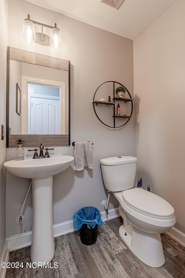 bathroom featuring wood-type flooring and toilet