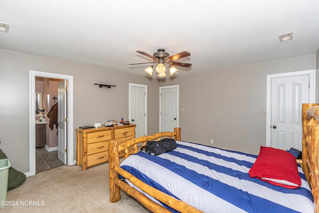 carpeted bedroom featuring connected bathroom, multiple closets, and ceiling fan