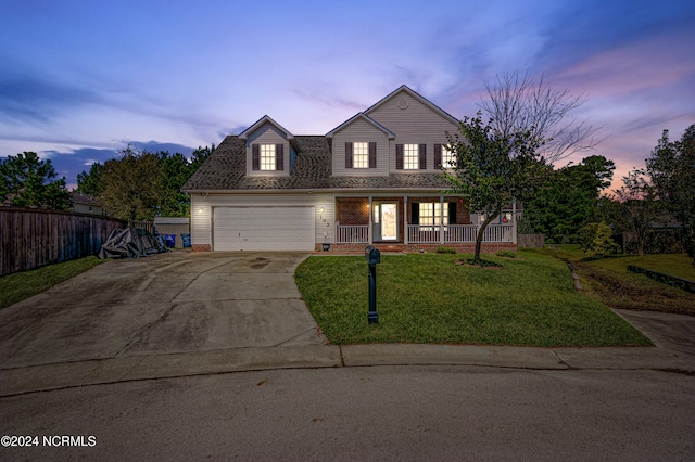 view of front of property featuring a garage, a yard, and covered porch