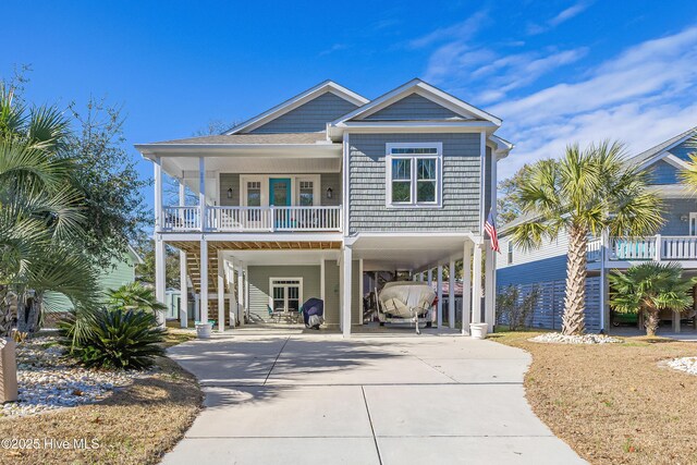 coastal home featuring a carport, stairway, concrete driveway, and covered porch