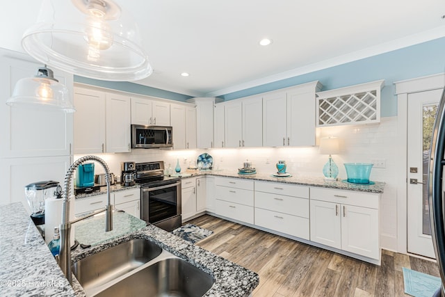 kitchen with light wood finished floors, white cabinetry, appliances with stainless steel finishes, and tasteful backsplash