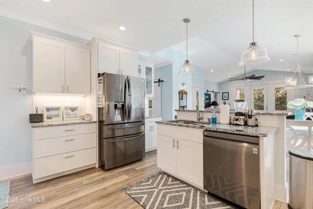 kitchen with light wood finished floors, white cabinets, a sink, a ceiling fan, and appliances with stainless steel finishes