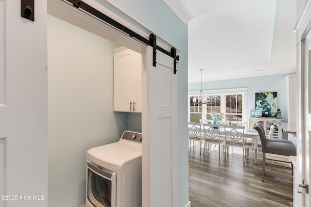 washroom with a barn door, wood finished floors, a chandelier, cabinet space, and washer / clothes dryer
