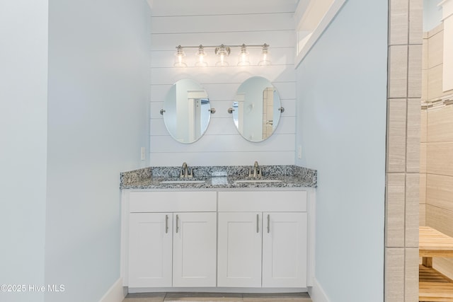 bathroom featuring double vanity, baseboards, and a sink
