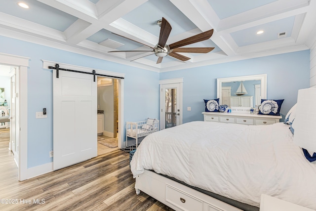 bedroom featuring light wood-type flooring, a barn door, coffered ceiling, and beamed ceiling