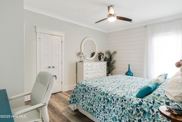 bedroom featuring a ceiling fan, wood finished floors, a closet, baseboards, and ornamental molding